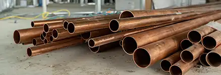 a pile of copper pipes sitting on top of a cement floor